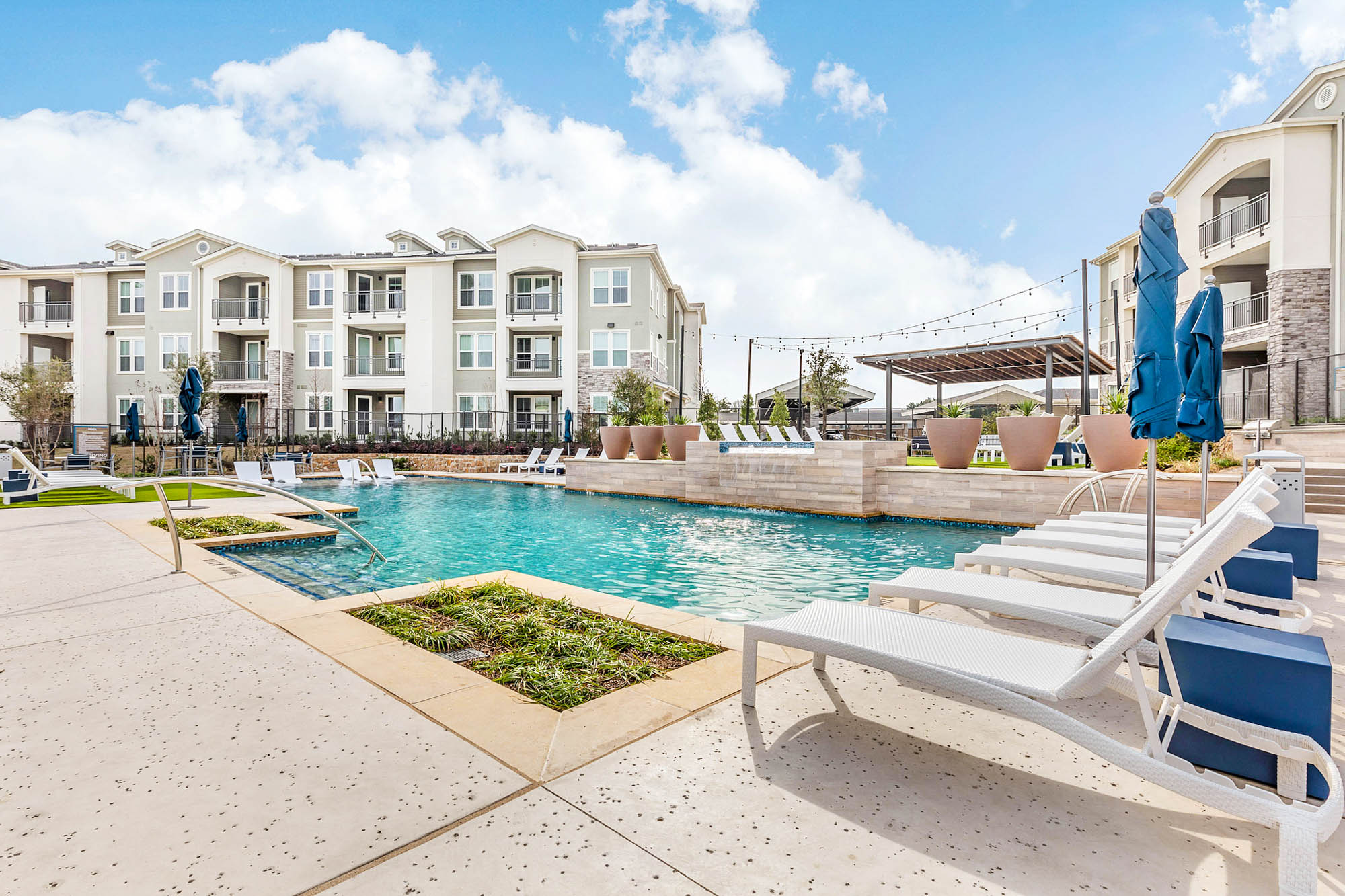 The exterior of an apartment building with a pool at Embree Hill in Dallas, TX.