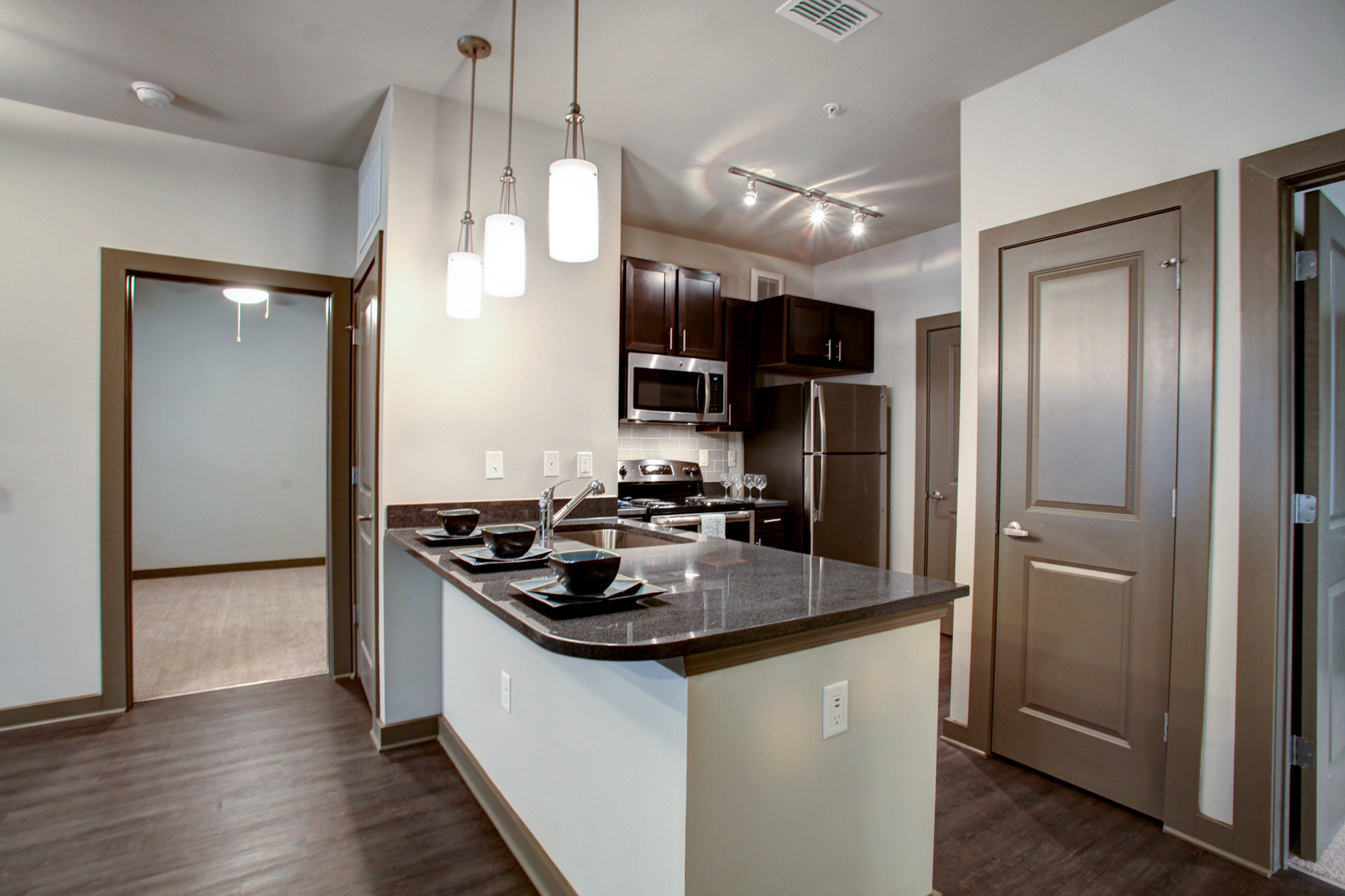 A kitchen island with stainless steel appliances and an open door on the left at Park 9 apartments.