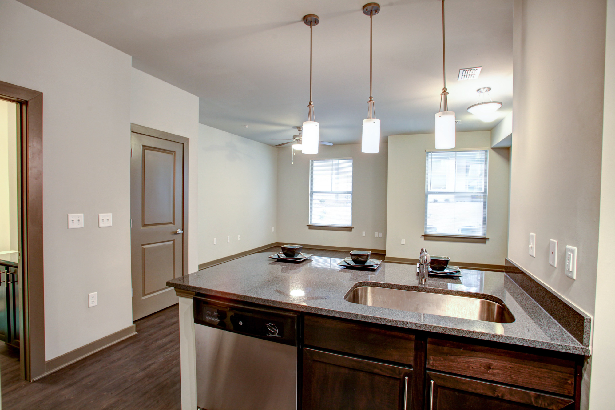 An empty apartment at Park 9 with pendant lighting and stainless steel appliances.
