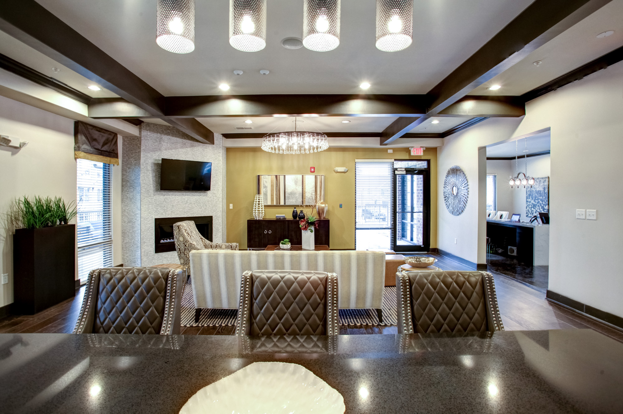 Three bar stools are in the foreground with a seating area, tv, and fireplace in the background.